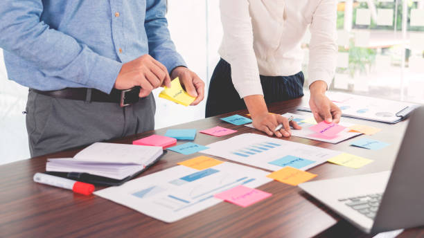 istock Businessman stick colorful notes to brainstorming on the table working on new project to share idea to thinking how to planning new case. 1279959650