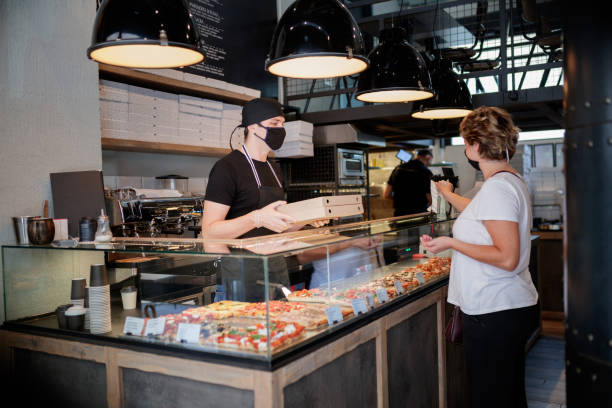 istock Checkout server about to give pizza box to customer who is using hand sanitazer 1279960012