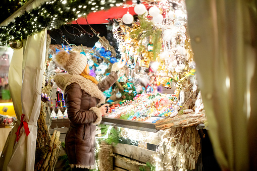 Woman holding a mug standing in warm clothes in front of Gendarmenmarkt Christmas street market stall in Berlin