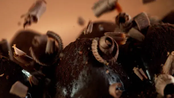 Detail of pralines with falling chocolate curls on top. Studio macro shot.