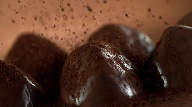 Detail of pralines with falling cocoa powder on top. Studio macro shot.