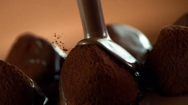 Detail of pralines with pouring melted chcocolate on top. Studio macro shot.