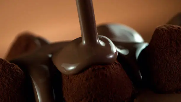 Detail of pralines with pouring melted chocolate on top. Studio macro shot.