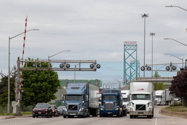 Trucks and vehicles seen leaving the Ambassador Bridge from Detroit entering Canada after crossing the US-Canada border, bridge seen in the background.