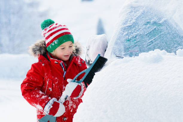 istock Child brushing off car. Kid with winter snow brush 1279962348