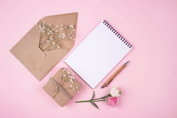istock Vintage flat lay composition with present box, blank copybook and kraft paper envelope on pastel pink background with copyspace. Holiday shopping list, bridal list or New Year Goals concept 1279965598