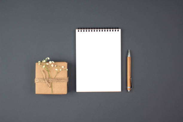 istock Vintage flat lay composition with present box, blank copybook and wooden pen on grey background with copyspace. Holiday shopping list, bridal list or New Year Goals concept, presents checklist 1279965602