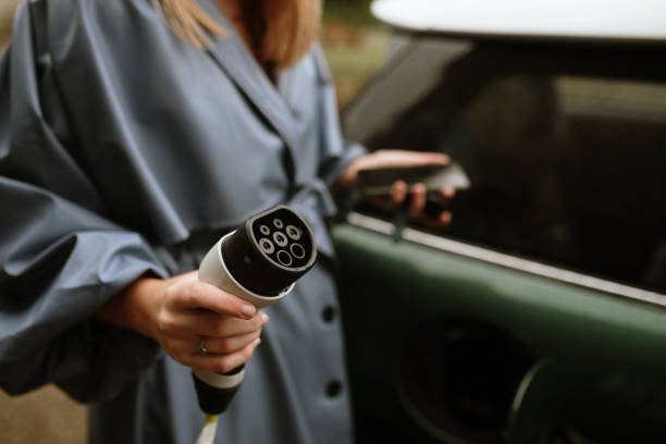 Young woman charging her electric car stock photo