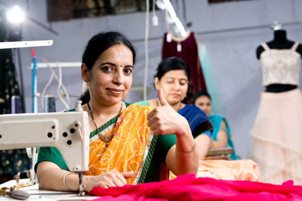 donna indiana operaia tessile che dà pollici in su sul posto di lavoro - working tailor stitch sewing foto e immagini stock