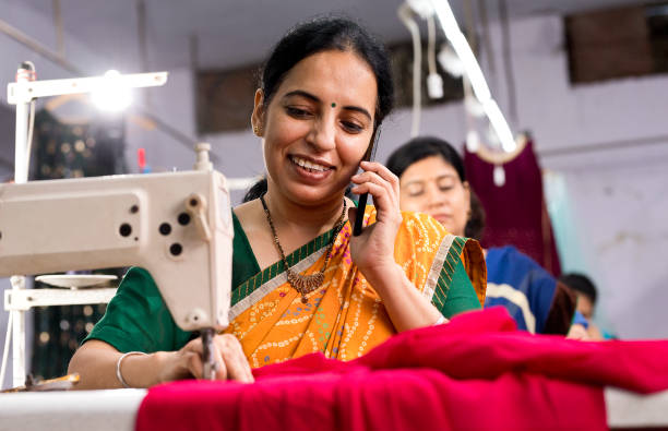 istock Indian woman textile worker talking on mobile phone while sewing dress fabric 1279972403