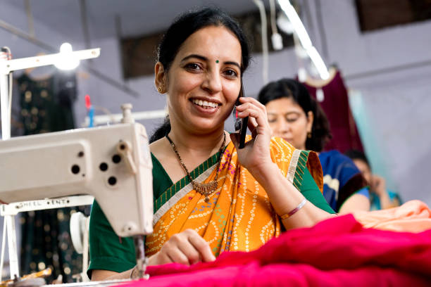 istock Indian woman textile worker talking on mobile phone while sewing dress fabric 1279972464