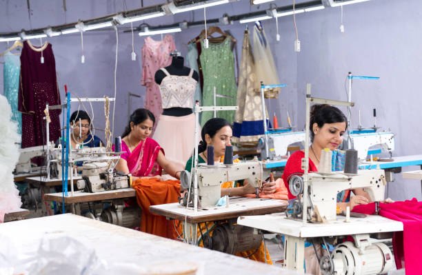 woman textile worker using sewing machine on production line - sewing tailor sewing machine women imagens e fotografias de stock