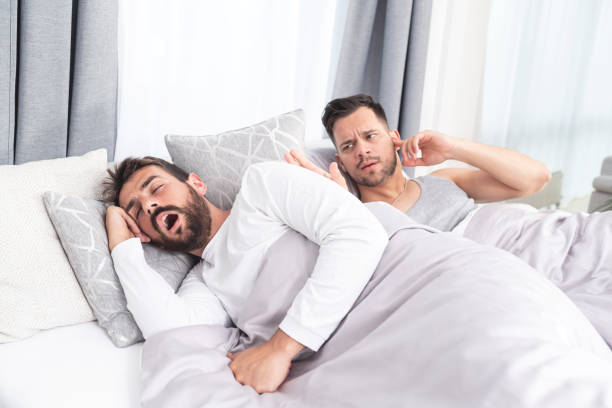 hombre gay roncando en voz alta como pareja molesta bloquea las orejas en la cama - couple love snoring sleeping fotografías e imágenes de stock