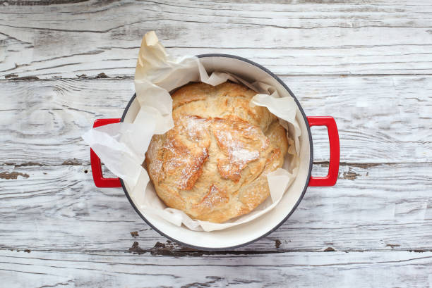 Fresh Artisan Bread in a Dutch Oven Top view of homemade artisan bread freshly baked in a red Dutch oven. Flatlay. baking bread photos stock pictures, royalty-free photos & images