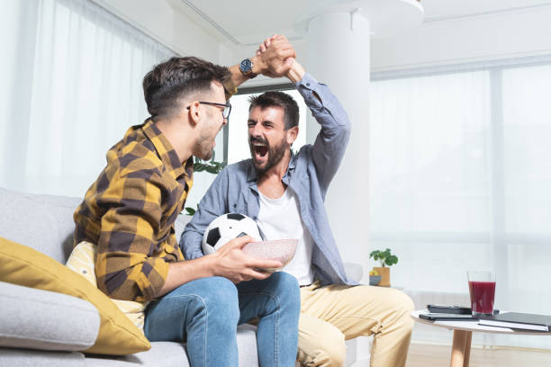 istock Two happy men doing victory clasp while watching football match 1279973066