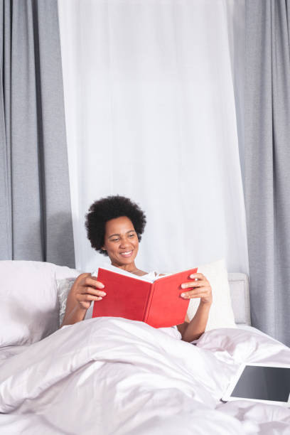 istock Woman reading a book lying on bed at home 1279975768