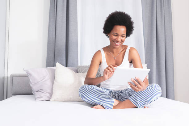 istock Woman using digital tablet sitting on bed at home 1279975788