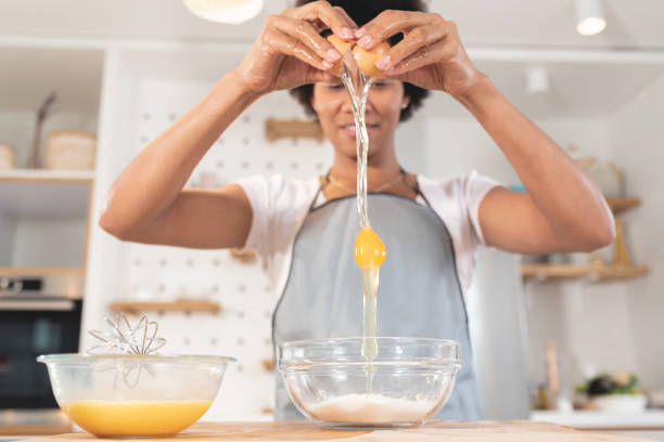 donna che rompe un uovo in una ciotola - break eggs domestic kitchen breaking foto e immagini stock