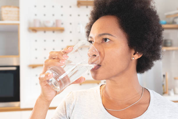 istock Woman drinking water at home 1279975943