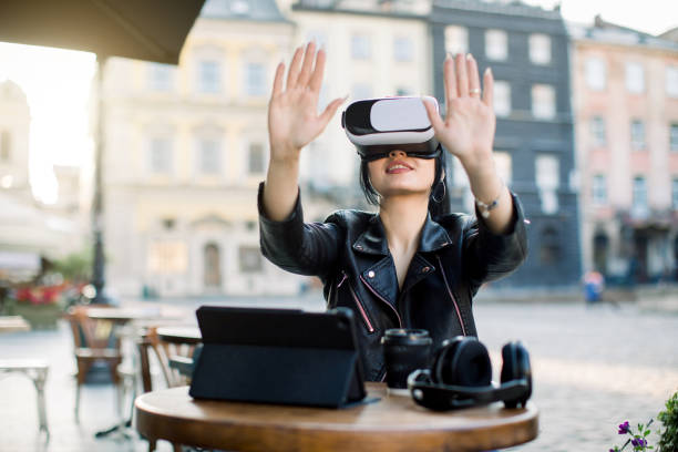 istock Smiling young attractive businesswoman moving hands while trying 3d virtual reality glasses at outdoor urban cafe in old city center. VR experience, work in VR, vr helmet for smartphone games 1279977894