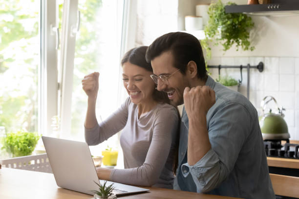 istock Overjoyed young married couple making yes gesture, looking at computer. 1279978019