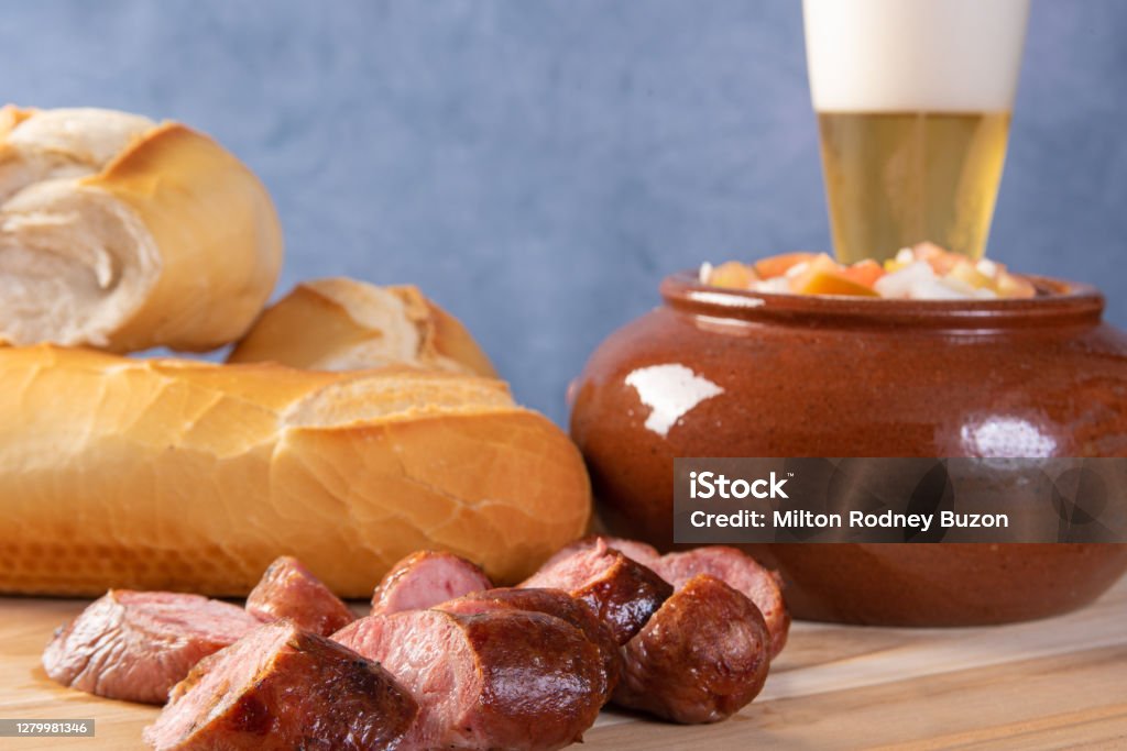 Breads, vinaigrette, sliced "u200b"u200broasted sausage and a glass of beer on a table, blue background, selective focus. Barbecue - Meal Stock Photo