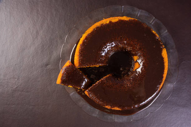 bolo de cenoura com cobertura de chocolate em uma placa de vidro sobre uma mesa, vista para cima. - cake carrot carrot cake dessert - fotografias e filmes do acervo
