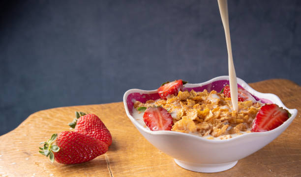 istock Breakfast cereal, corn flakes, strawberries in a bowl on rustic wood, pouring milk. selective focus. 1279981761