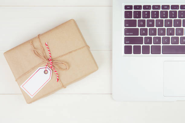 istock Gift box with paper kraft and having tag while laptop computer on wooden table, present giving for Christmas day or birthday, season and celebrate, top view, flat lay, online shopping concept. 1279983078