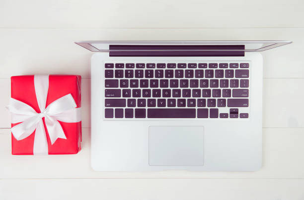 istock Red gift box and having laptop computer on wooden table, present giving for Christmas day or anniversary or birthday, season and celebrate, top view, flat lay, online shopping concept. 1279983099