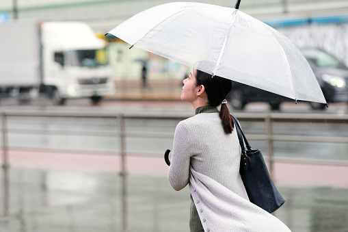 Asian woman walking on street in rainy day