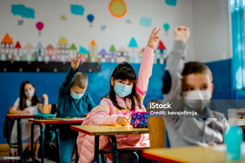 Elementary schoolchildren wearing a protective face masks  in the classroom. Education during epidemic. School Building Stock Photo