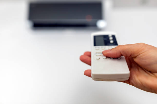 istock Hand with remote control directed on air conditioner inside the room 1279986612