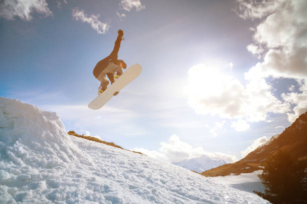 młody człowiek w okularach przeciwsłonecznych robi sztuczkę w locie z kicker śniegu na tle gór - skiing winter sport powder snow athlete zdjęcia i obrazy z banku zdjęć