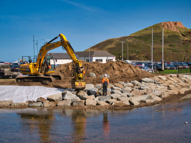 der bau von hochwasserschutzanlagen entlang skelton beck mit schweren erdbewegungsgeräten und großen steinblöcken - erosionskontrolle stock-fotos und bilder