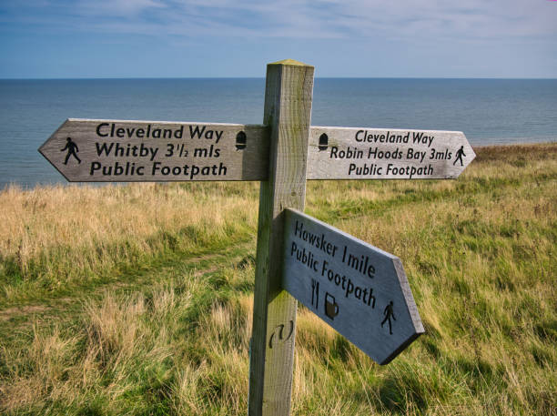 A wooden signpost on a coastal section of the Cleveland Way national trail between Robin Hood's Bay and Whitby in North Yorkshire, England, UK - taken on a sunny day A wooden signpost on a coastal section of the Cleveland Way national trail between Robin Hood's Bay and Whitby in North Yorkshire, England, UK - taken on a sunny day cleveland england stock pictures, royalty-free photos & images