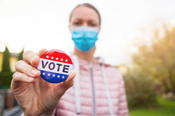 istock Woman showing elections sticker with face mask 1279992095