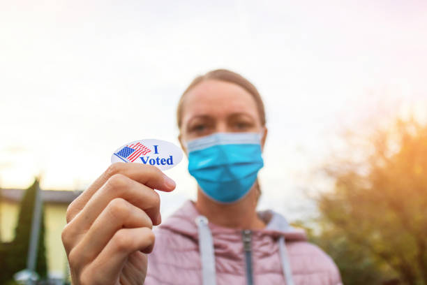 istock Woman showing elections sticker with face mask 1279992097
