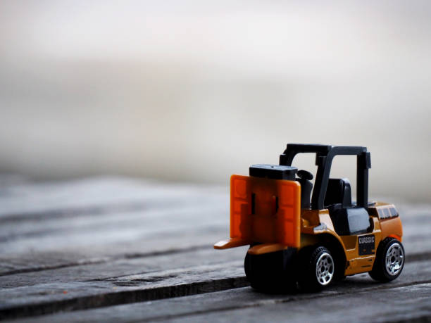 istock Miniature yellow forklift model on wooden table. Warehouse logistics business or construction 1279992103