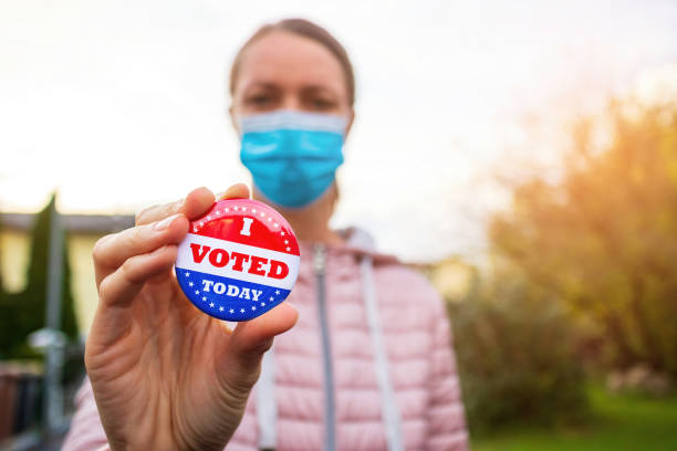 istock Woman showing elections sticker with face mask 1279992121
