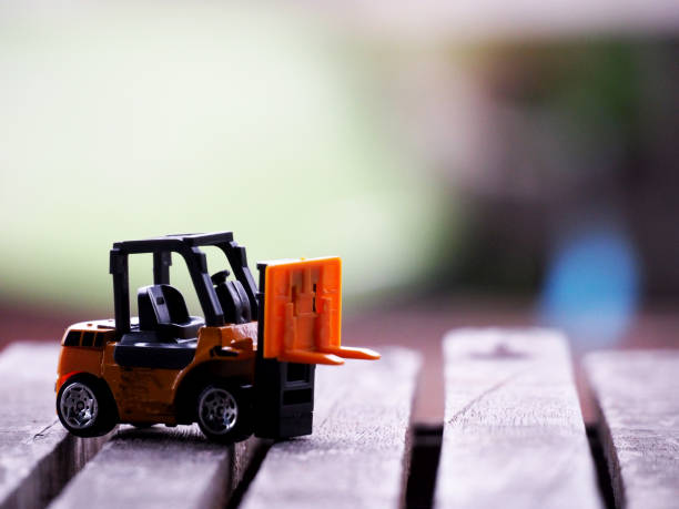 istock Miniature yellow forklift model on wooden table. Warehouse logistics business or construction 1279992130
