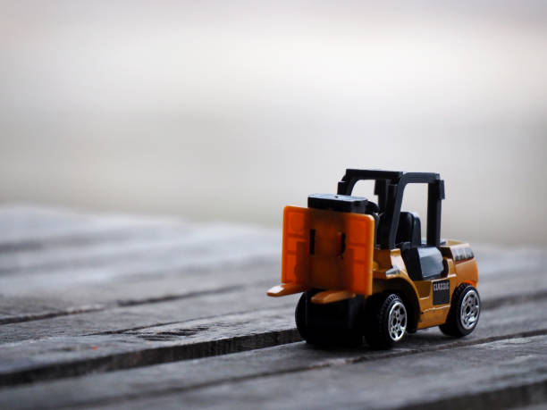 istock Miniature yellow forklift model on wooden table. Warehouse logistics business or construction 1279992189