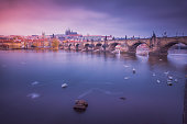 Charles Bridge illuminated at dawn and blurred swans – ethereal Prague, Czech Republic