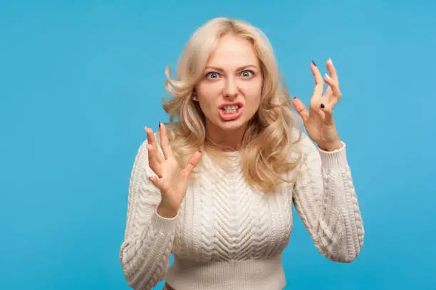 Photo of Aggressive stressed blond woman arguing and becoming mad clenching teeth, crazy furious lady in depression