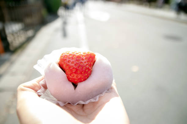 istock Hand holding a Strawberry Diafuku (Ichigo Daifuku or mochi) with red bean paste inside. Japanese traditional dessert. 1280001209