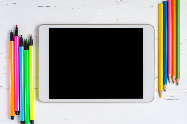 istock A tablet with an empty screen and office supplies on a white wooden background. Concept app for school children or online learning. Copy space 1280003880