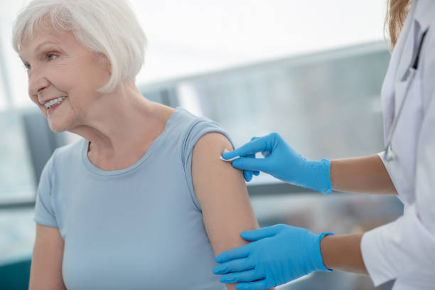 istock Nurse making an injection to an elderly smiling woman 1280005160