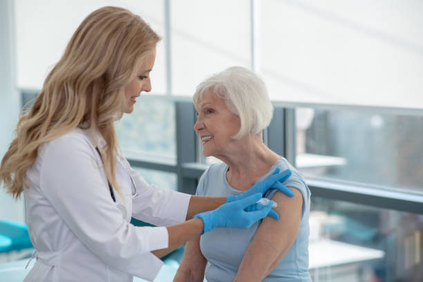 istock Long-haired smiling nurse making vaccination to an elderly woman 1280005170