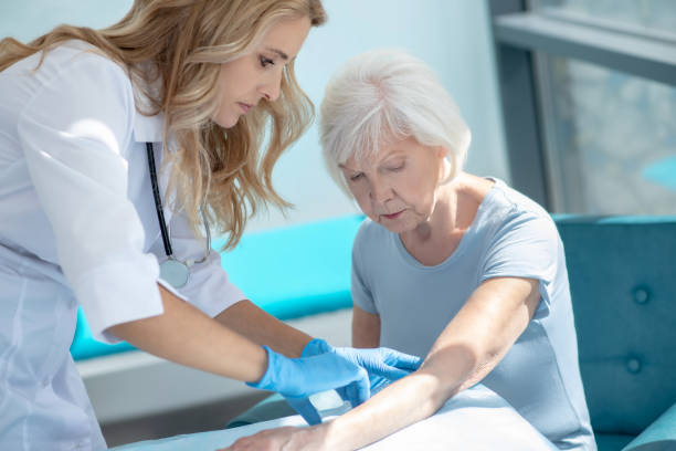 istock Long-haired smiling nurse making injection to an elderly woman 1280005179