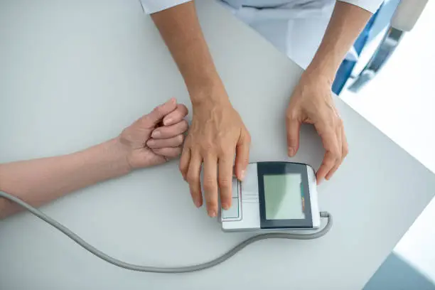 Blood pressure. Close up of doctors hands measuring blood-pressure to a patient